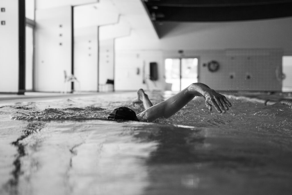 Atleta nadando en piscina, brazo fuera. Promoción para Orca Sportswear